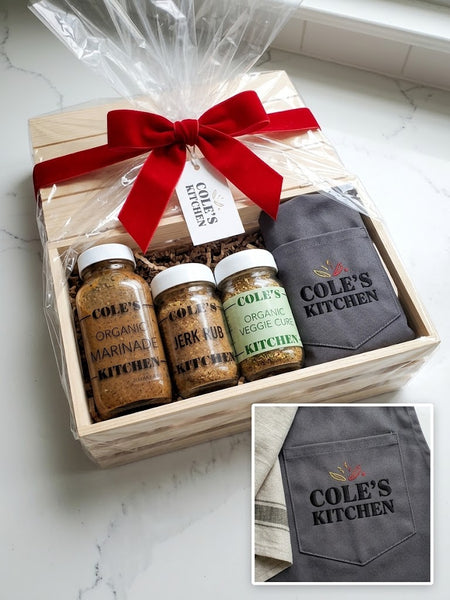 Bespoke holiday gift crate featuring Cole's Kitchen gourmet marinades and spice rubs alongside a Northern Loom embroidered chef apron and kitchen towel.