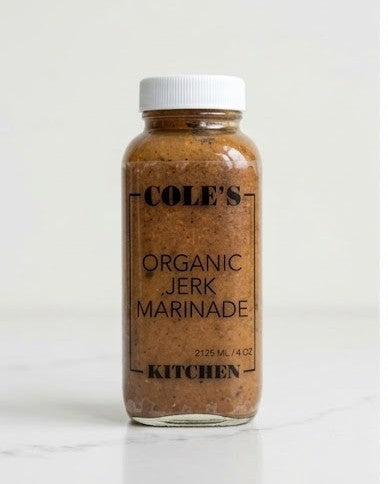 A glass bottle of Cole's Organic Jerk Marinade with a white cap, set against a clean white background.