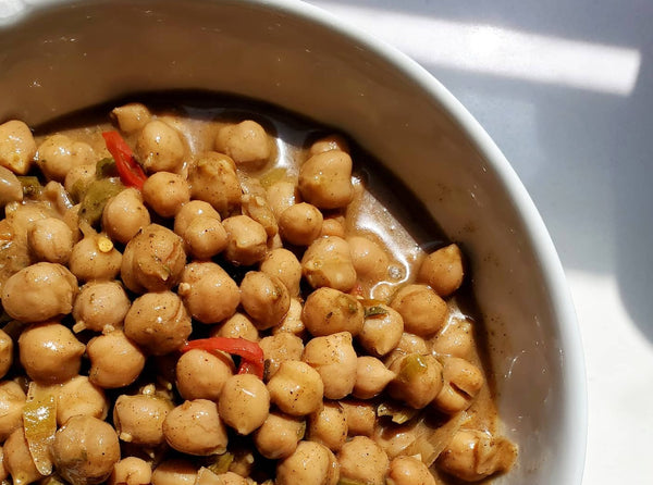 A bowl of savory chickpeas simmered in a rich sauce made with Cole's Kitchen Organic Jerk Spice Rub, highlighting the versatile use of the Caribbean spice blend for plant-based meals.
