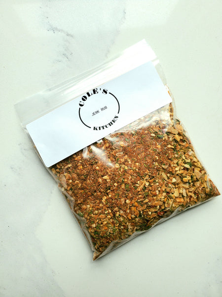 A clear resealable refill pouch of Cole's Kitchen Organic Jerk Spice Rub with a white brand label, showing the vibrant spice blend inside.