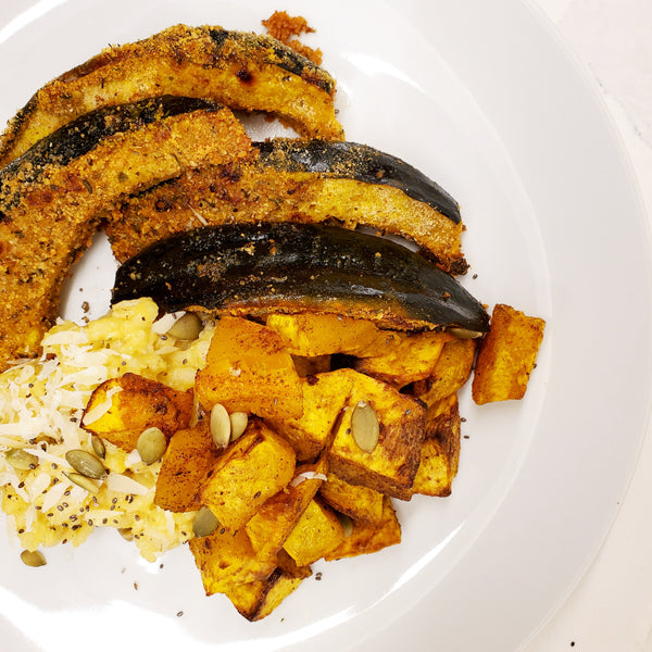 A white plate featuring roasted acorn squash slices and diced potatoes seasoned with Cole's Kitchen Veggie Cure Spice Blend, served over a bed of white rice with pumpkin seeds.